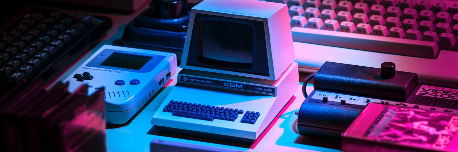 Vintage Commodore CBM, Game Boy, and keyboards lit in magenta and cyan